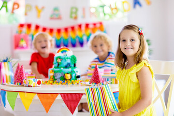 Child birthday party. Kids blow candle on cake.