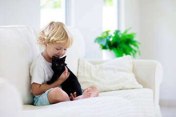 Child playing with baby cat. Kid and kitten.