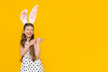 Obraz na płótnie Canvas Masquerade Easter bunny ears on a beautiful little girl on a yellow isolated background. A girl with the face of an Easter bunny.