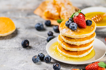 Pancakes in a plate with berries and honey. 