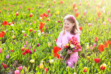 Obraz na płótnie Canvas Little girl in tulip flower garden