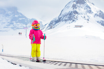 Child on ski lift in snow sport school in winter mountains