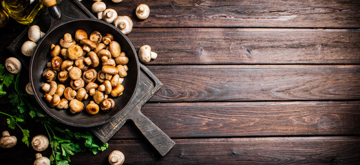 Fragrant homemade fried mushrooms in a frying pan on a cutting board. 