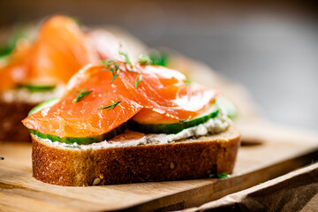 Salmon sandwich on a wooden cutting board. 