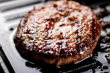 Cooking a delicious grilled burger on a pan with oil bubbles.
