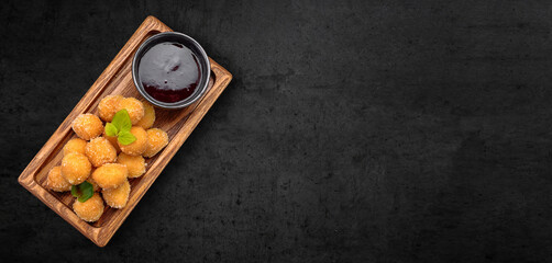 Cheese nuggets with fruit jam, on a wooden board. Banner