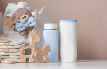 Wooden toys, a bear in a bow tie, a stack of diapers, bottles without labels and baby supplies on the changing table. Space for text.