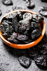 Prunes in a wooden plate on the table. 