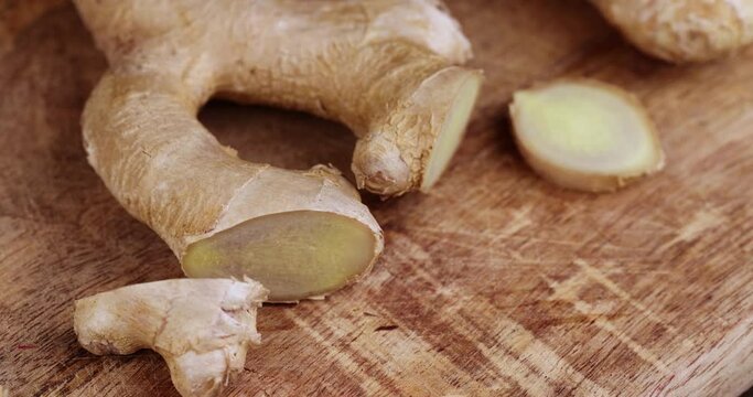Sliced pieces of ginger root on the table, cooking a dish using ginger root which is cut with a knife