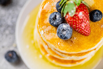 Pancakes with honey and berries on a plate.