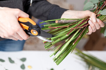 florist cuts the stems of flowers in a bouquet of pruning shears