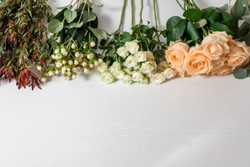 flowers and greens on the edge of a white wooden table