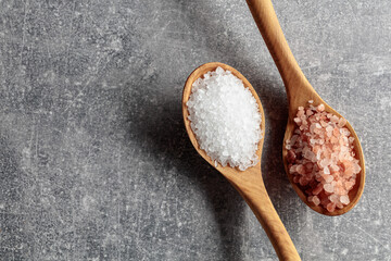 Pink and sea salt in wooden spoons.
