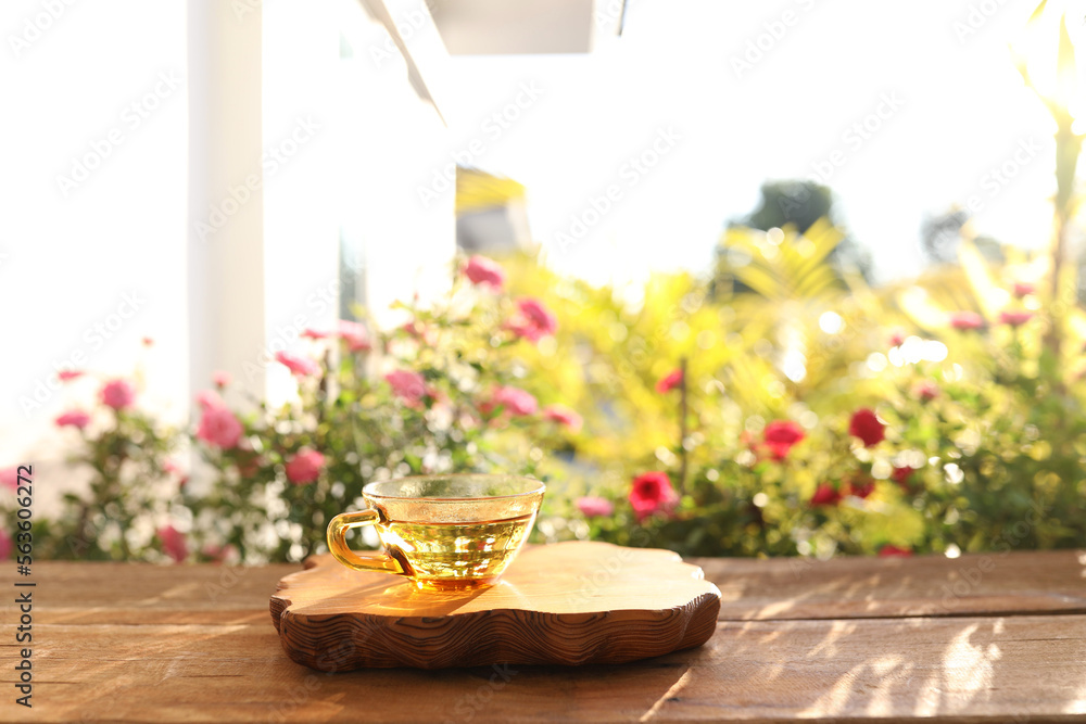 Sticker Tea in a golden glass cup and spoon on a wooden tray with flowers background