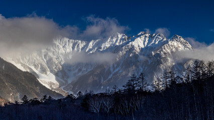 雲間から顔を出す雪の穂高連峰　冬の上高地