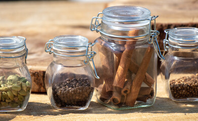 Seasonings in glass jars on a wooden table.