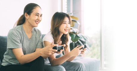 Two young adult woman couple living together with relationship asian people using gamepad playing a game