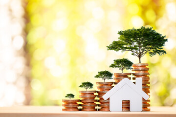 Home model with presenting and stack gold coins and tree growing on the top in public park, Saving...