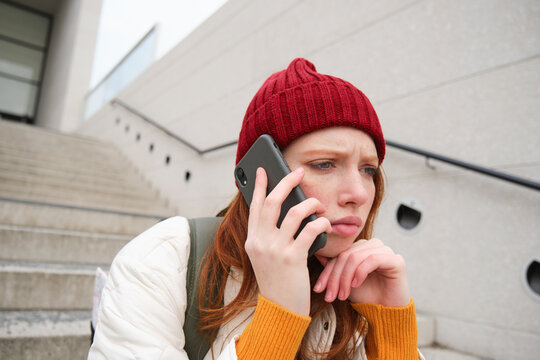 Portrait Of Worried Girl Calls Somebody With Concerned Face, Being On A Phone, Receives Bad News, Looking Upset By Conversation On Smartphone