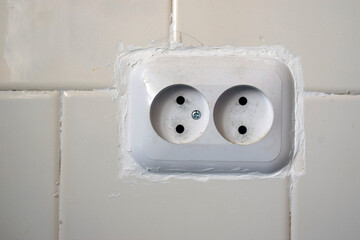 White double socket in a tiled wall.