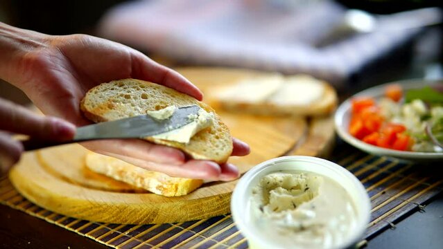 spreading cream cheese with knife on multigrain bread 