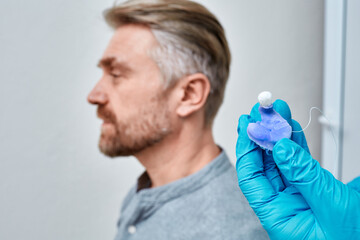 Audiologist holding molded individual earmolds for hearing aids of patient in hand, close-up....