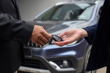 Close-up image of hands of client buys a car and receives keys from the car dealer sales.