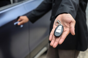 Unrecognizable salesman offering car key selling auto in dealership store.
