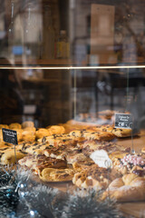 Sweets seen through the shop window. Shop window of a patisserie or bakery with croissants, apple pies and waffles. Freshly baked pastries. Label with 