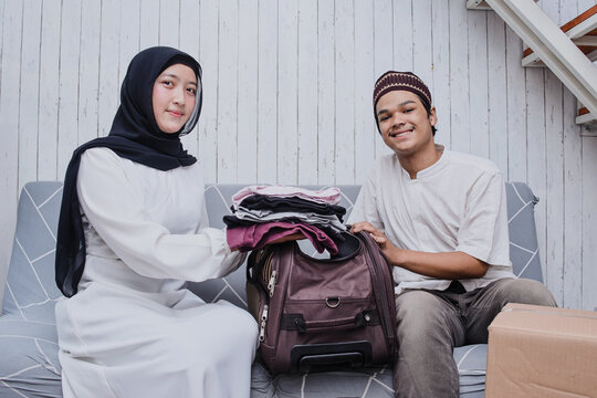 Muslim couple put stuff in suitcase. concept of man and woman travelling for Eid Mubarak celebration. - Powered by Adobe