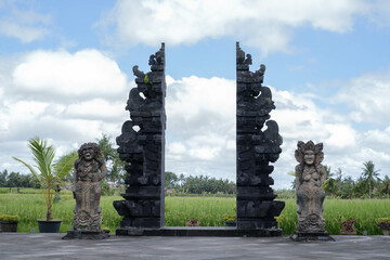 Balinese mini gate building or usually called Gapura with statues made of stone in each side in a...