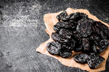 A bunch of delicious prunes on paper on the table. 