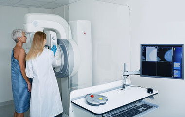 Mammogram procedure in medical clinic, mammography. Female mammologist positions mature woman at...