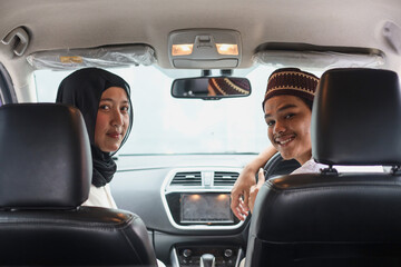 Muslim couple are smiling inside the car ready to go on holiday. Mudik lebaran at Eid moment. 