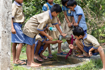 Indian Rural School Students drinking water from Tubewell at village - obrazy, fototapety, plakaty