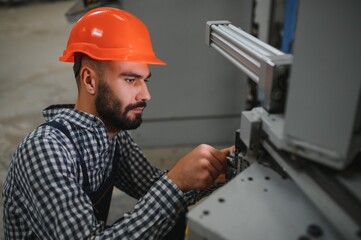 Portrait of industrial engineer. Factory worker with hard hat standing in factory.