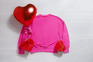 Pink sweatshirt mockup. Valentines Day concept shirt, balloons heart shape on wooden background. Copy space, template blank front view clothes. Romantic outfit. Flat lay birthday holiday fashion
