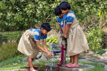 Indian Rural School Girls drinking water from Tubewell at village - obrazy, fototapety, plakaty