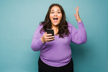 Excited obese woman receiving exciting news on her phone