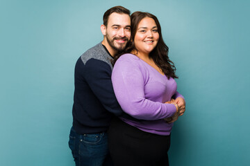 Fototapeta premium Happy couple of a big woman and a Caucasian man hugging in a studio