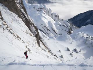 Lonely free-rider skier in high mountains. Extreme freestyle skiing in sunny daylight on winter mountain landscape