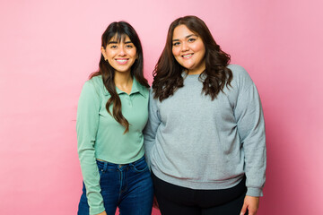 Happy best friends posing in a pink background