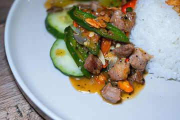 Stir-fried pork meat with Indonesian herbs and spices and white rice on a white plate. Bokeh background. Shallow depth-of-field.