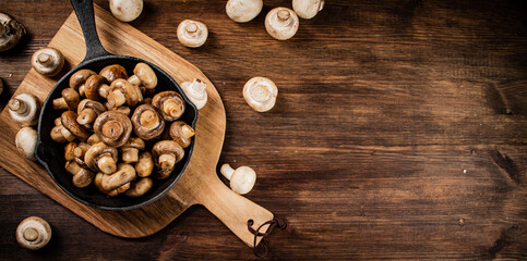 Fried mushrooms in a frying pan on a cutting board. 