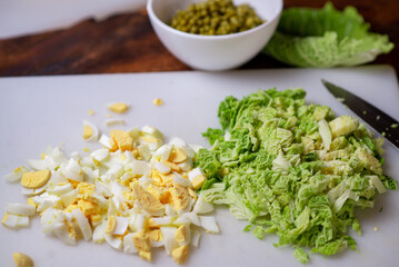 Preparation of a vegetarian savoy cabbage salad. Chopped chicken eggs and savoy cabbage on a cutting board.