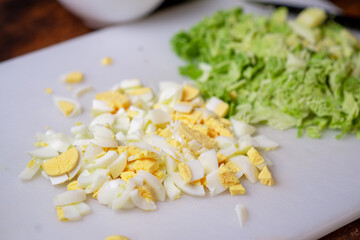 Preparation of a vegetarian savoy cabbage salad. Chopped chicken eggs and savoy cabbage on a cutting board.