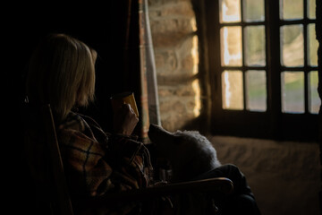 A woman sits near the window with a cup of coffee. Loneliness, sadness concept. Midlife crisis, reflections.