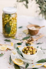 Various olives flavored with spices in white cup and glass jar. Green olives, black olives. Front and top shot on a white background