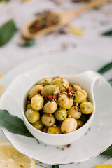 Various olives flavored with spices in white cup and glass jar. Green olives, black olives. Front and top shot on a white background