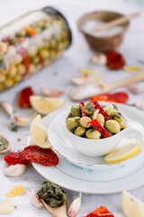 Various olives flavored with spices in white cup and glass jar. Green olives, black olives. Front and top shot on a white background